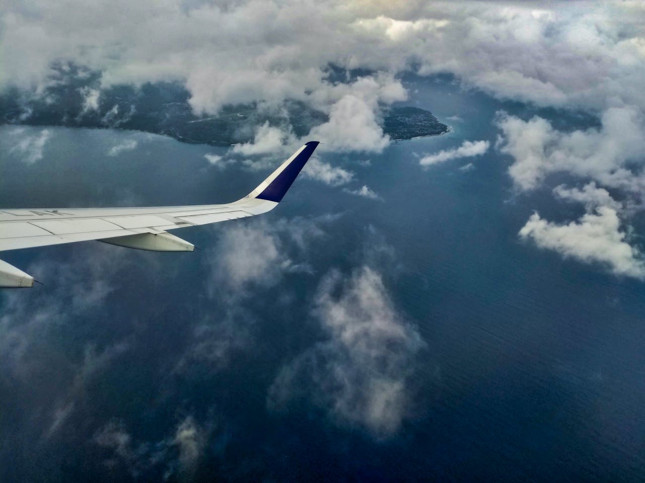 services-03 An airplane wing flying over the cloudy coastline of Aceh, Indonesia.